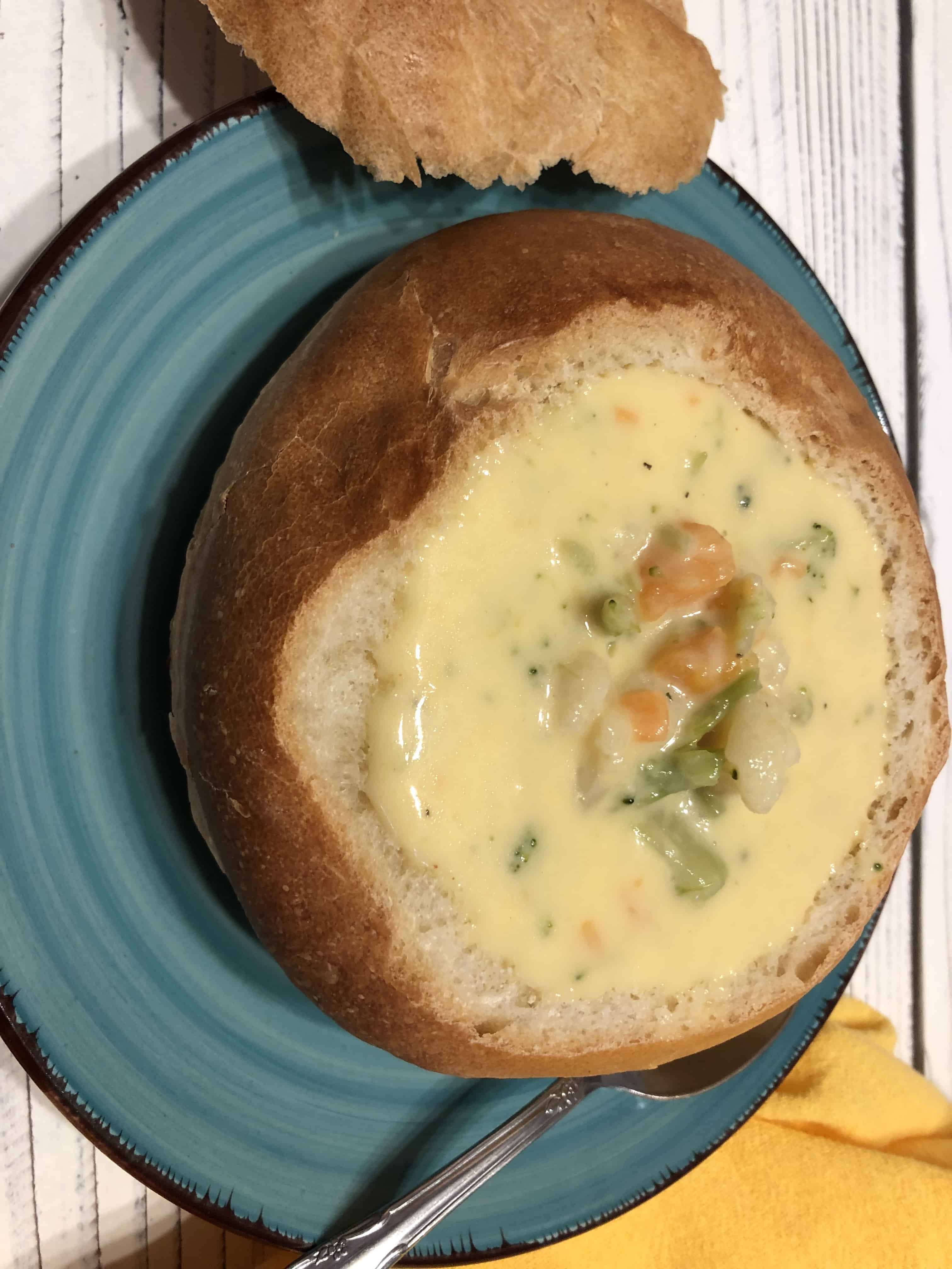Homemade Bread Bowl filled with Cheesy Broccoli & Cauliflower Soup served on a plate.