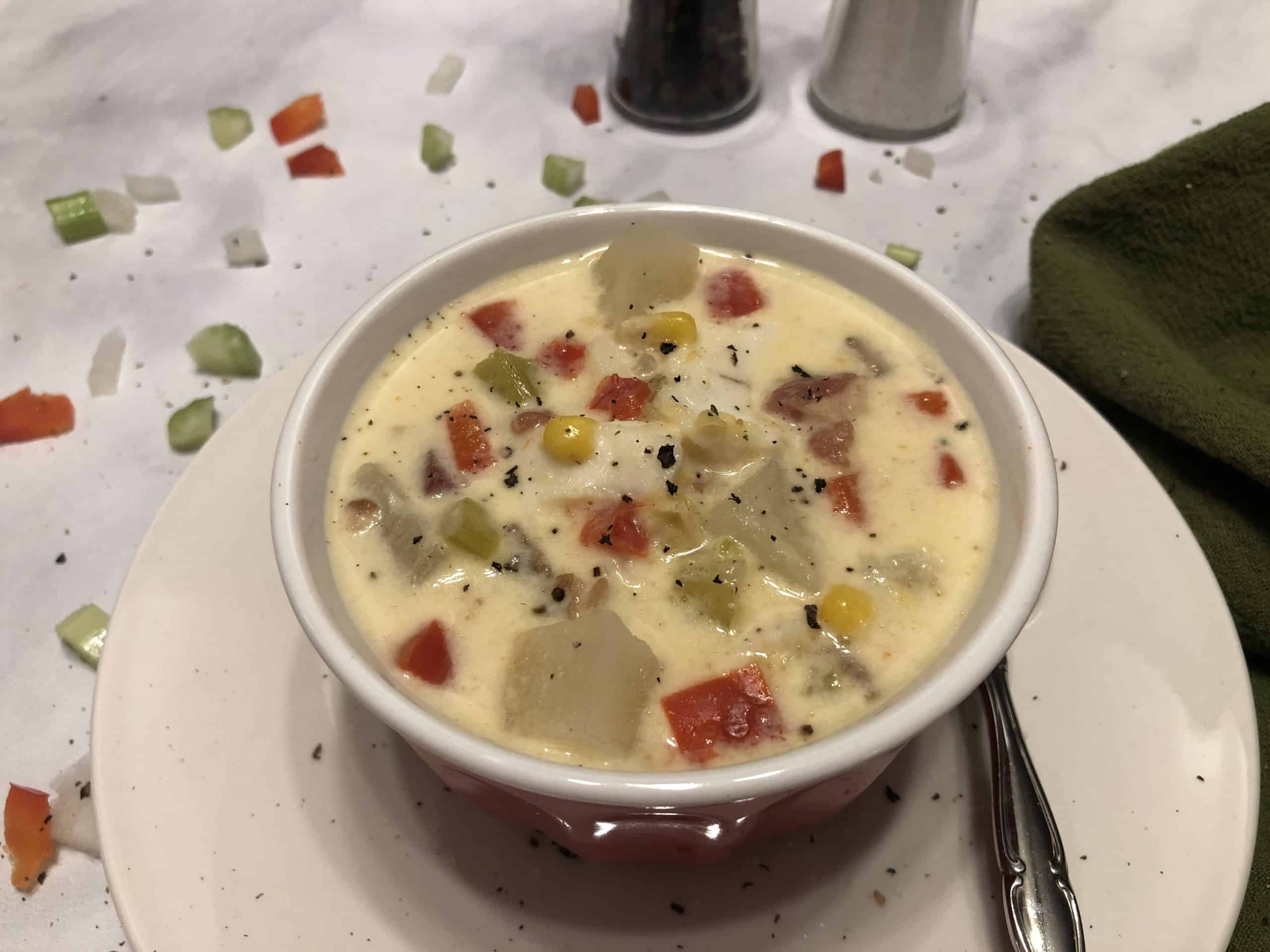 Bowl of Fish Chowder with red peppers, celery, potatoes, and onions.