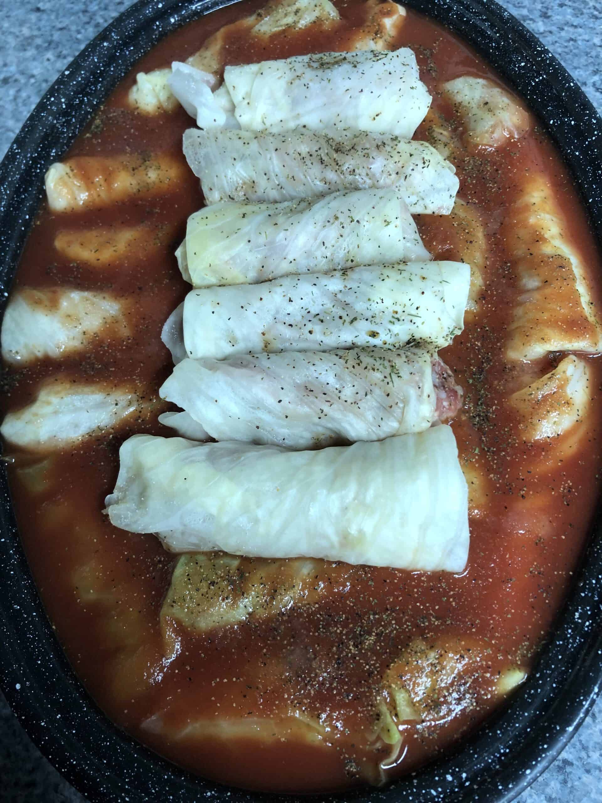 Several cabbage rolls lined up in a roasting pan.