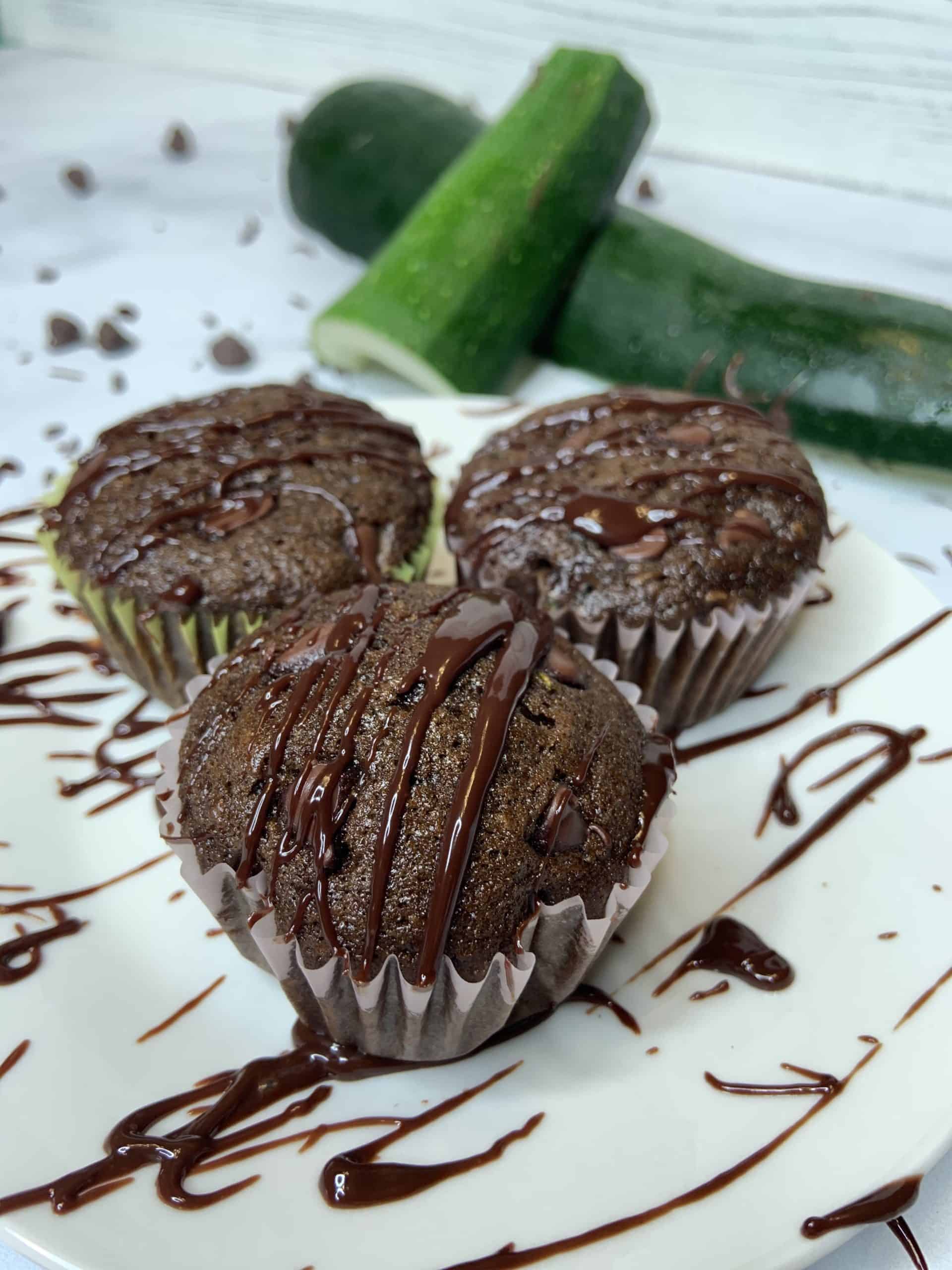 3 Gluten Free Chocolate Zucchini Muffins on a plate drizzled with ganache