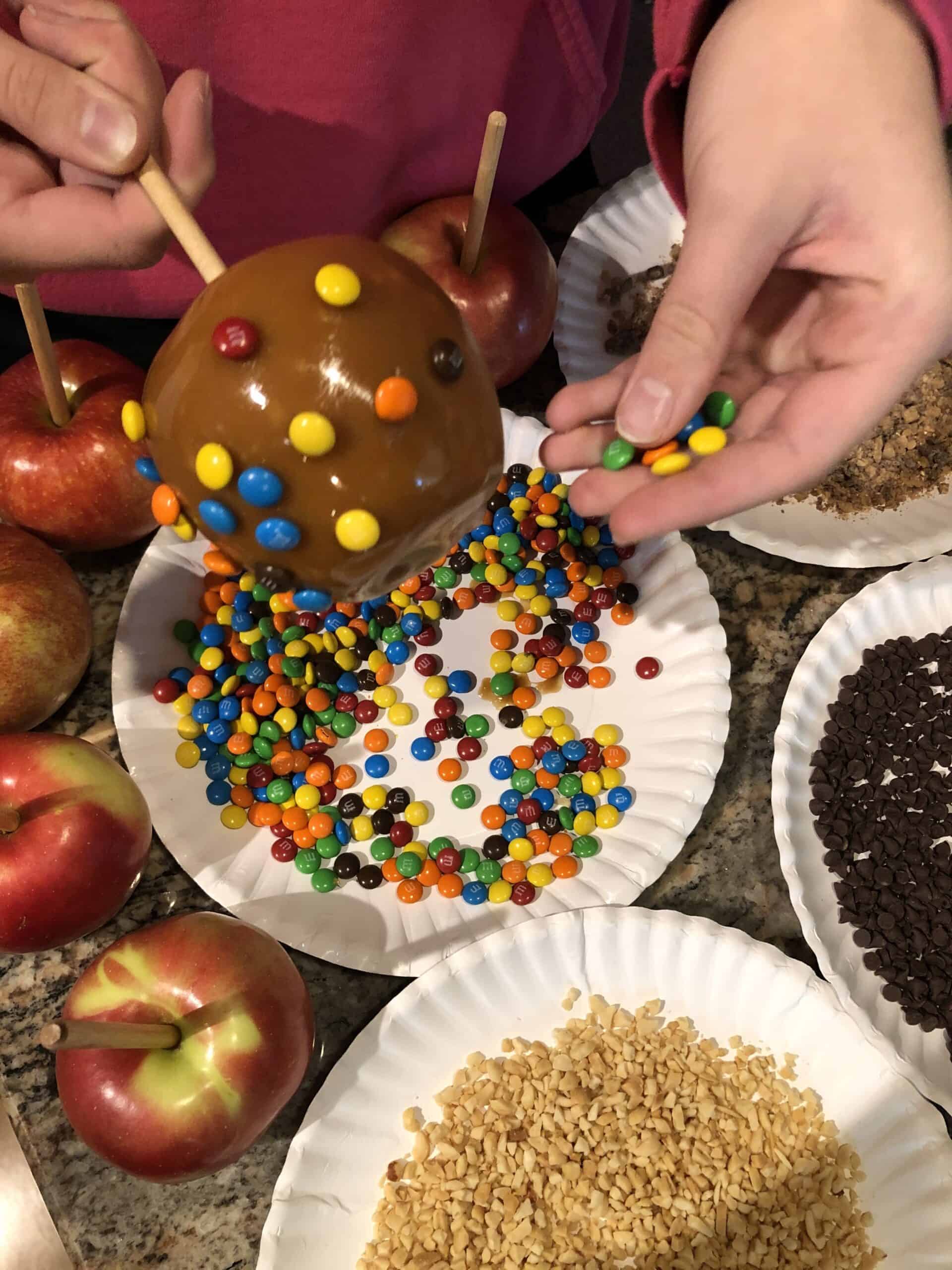 Adding your topping to the caramel apple.