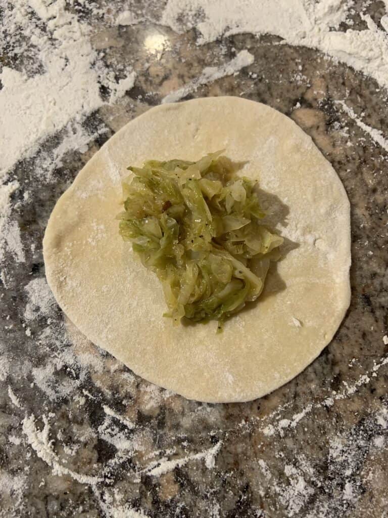 Cabbage filling on dough circle.