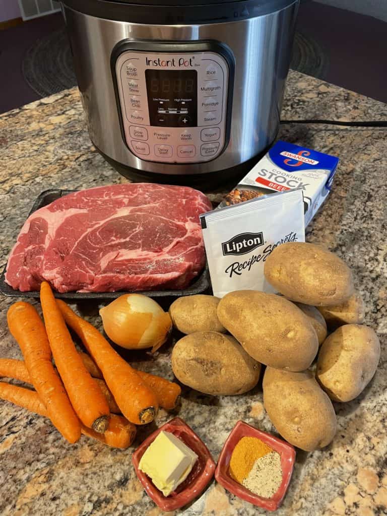 Pot Roast ingredients - roast, carrots, onion, potatoes, beed stock, onion soup mix, butter and seasonings.