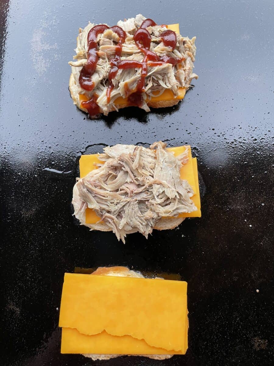 Assembling a pulled pork griddle sandwich in steps, butter one side of bread, place on hot Blackstone Griddle, add sliced cheese, pulled pork, and a drizzle of BBQ sauce.