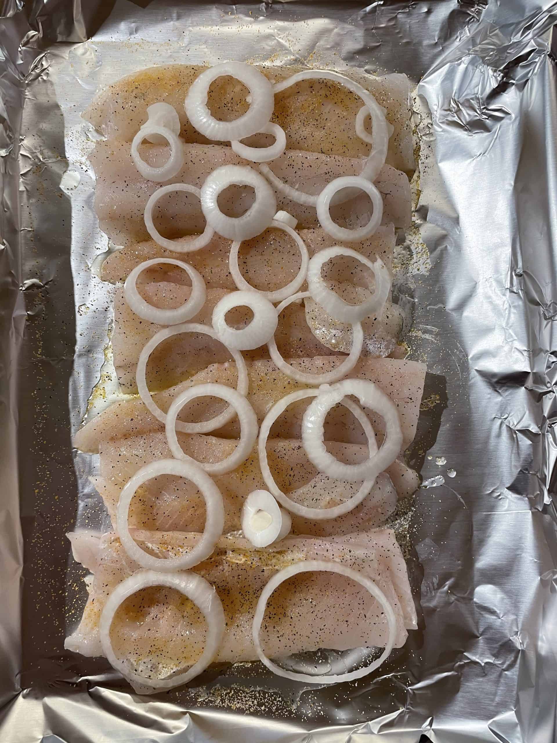 Sliced onion on-top of walleye fillets.