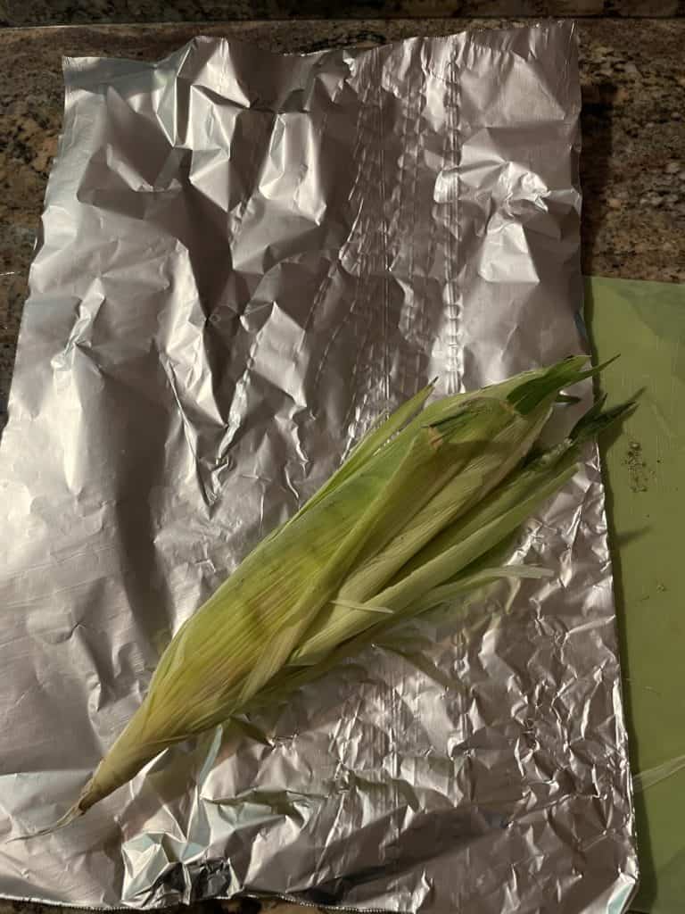 Place buttered corn cob onto the corner of a piece of foil.