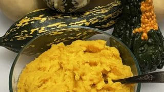 Mashed Butternut Squash in a bowl with an assortment of squashes in the background.