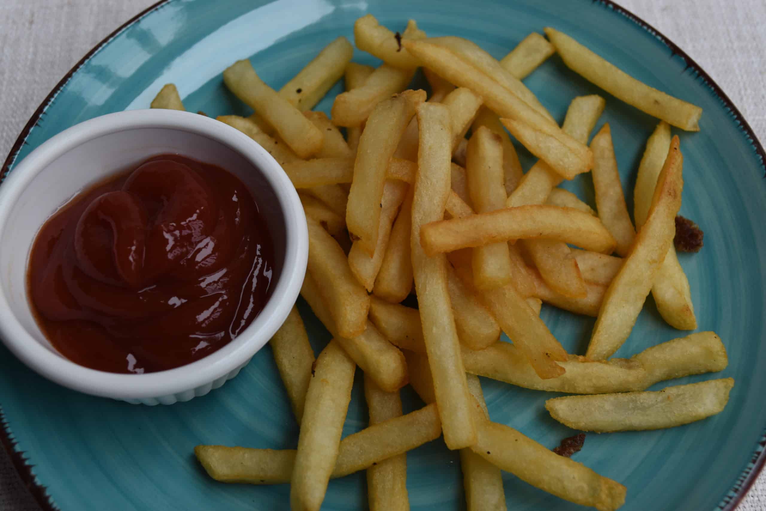 Blackstone Griddle Deep-Fried Frozen Fries on a plate with a cup of ketchup.