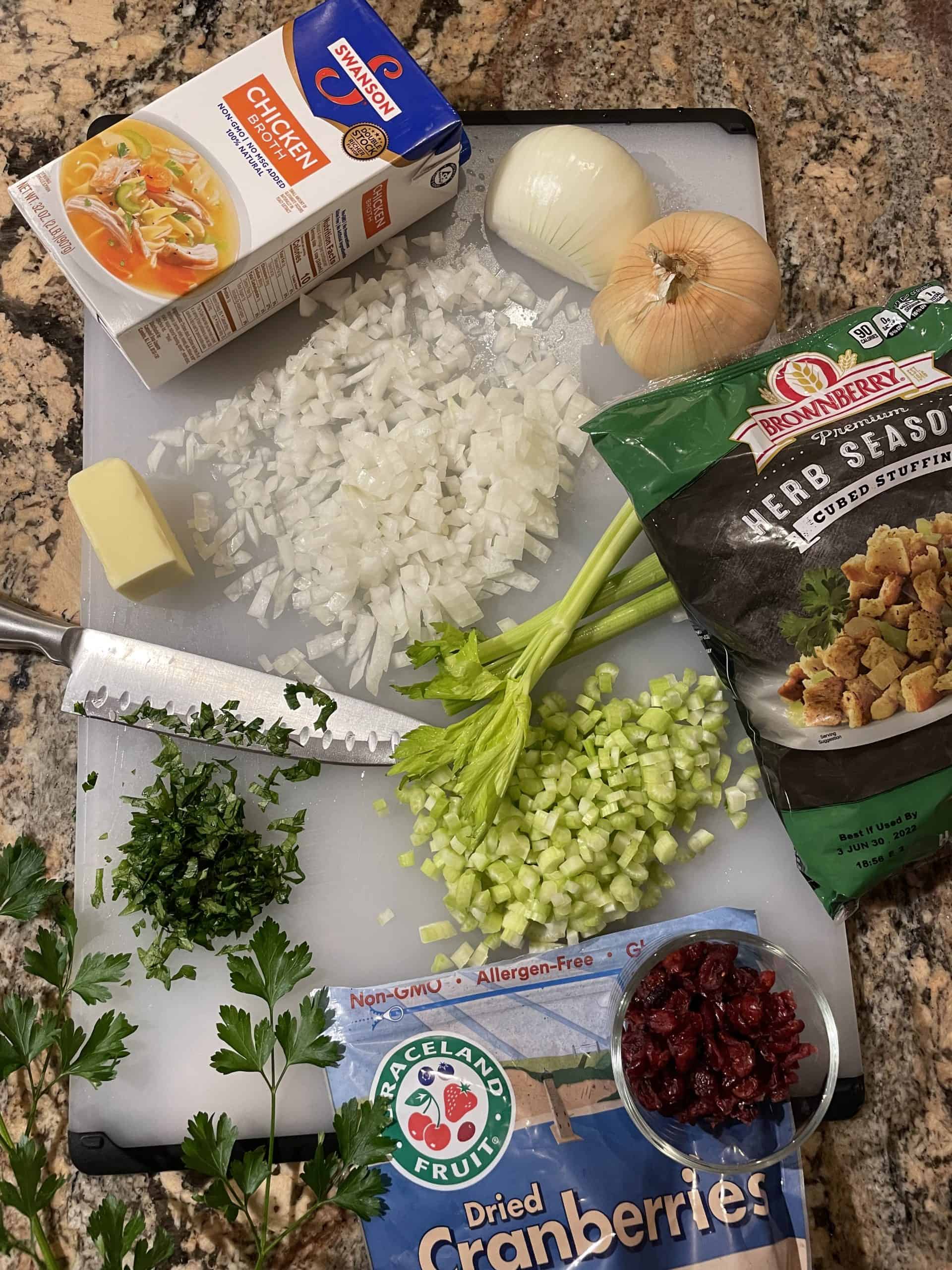 Traditional Stuffing Recipe Ingredients - diced celery, onion, broth, bag of stuffing mix, butter, fresh parsley, and dried cranberries. 