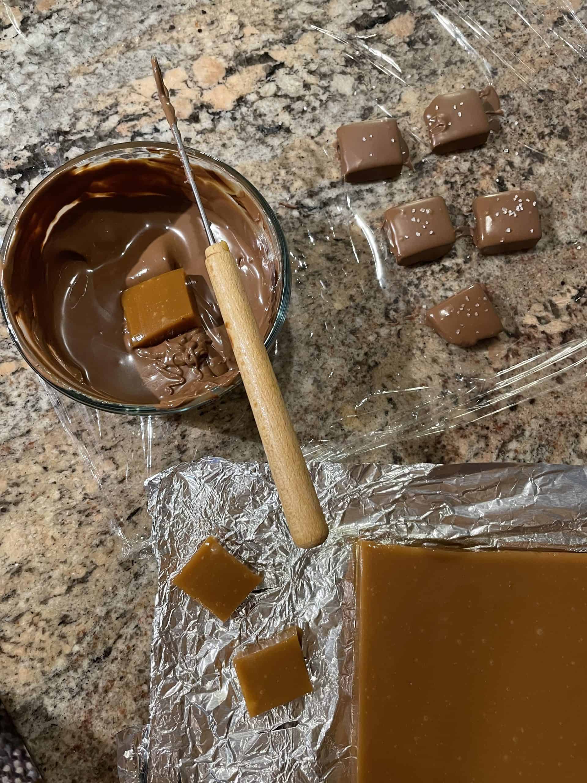 Dipping caramels in chocolate then top with sea salt.