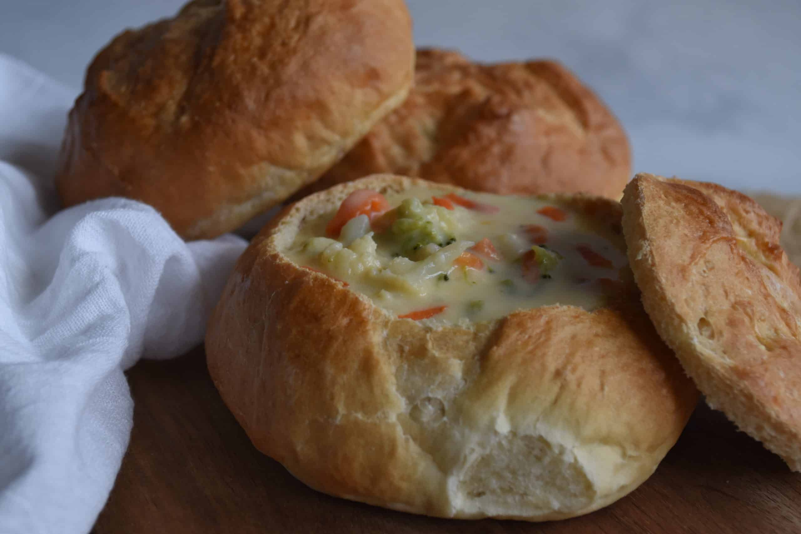 Homemade Bread Bowl filled with Cheesy Broccoli Cauliflower Carrot Soup with 2 extra bowls.