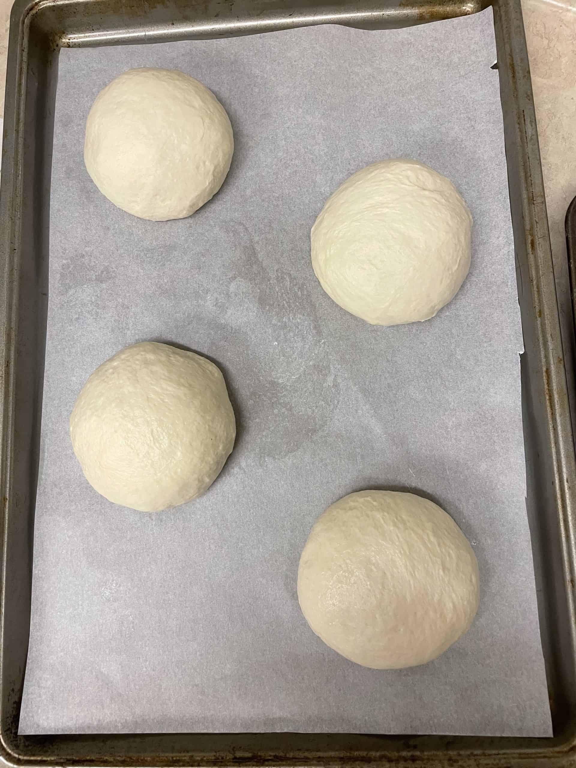 Four Dough Balls on a Parchment Lined Baking Sheet.