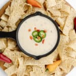 A pan full of white queso dip surrounded by tortilla chips.