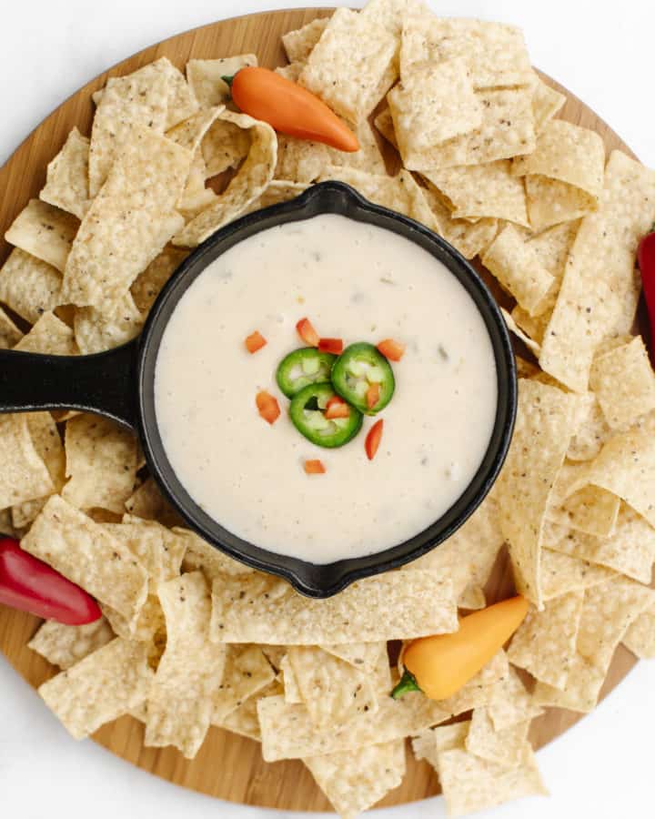 A pan full of white queso dip surrounded by tortilla chips.