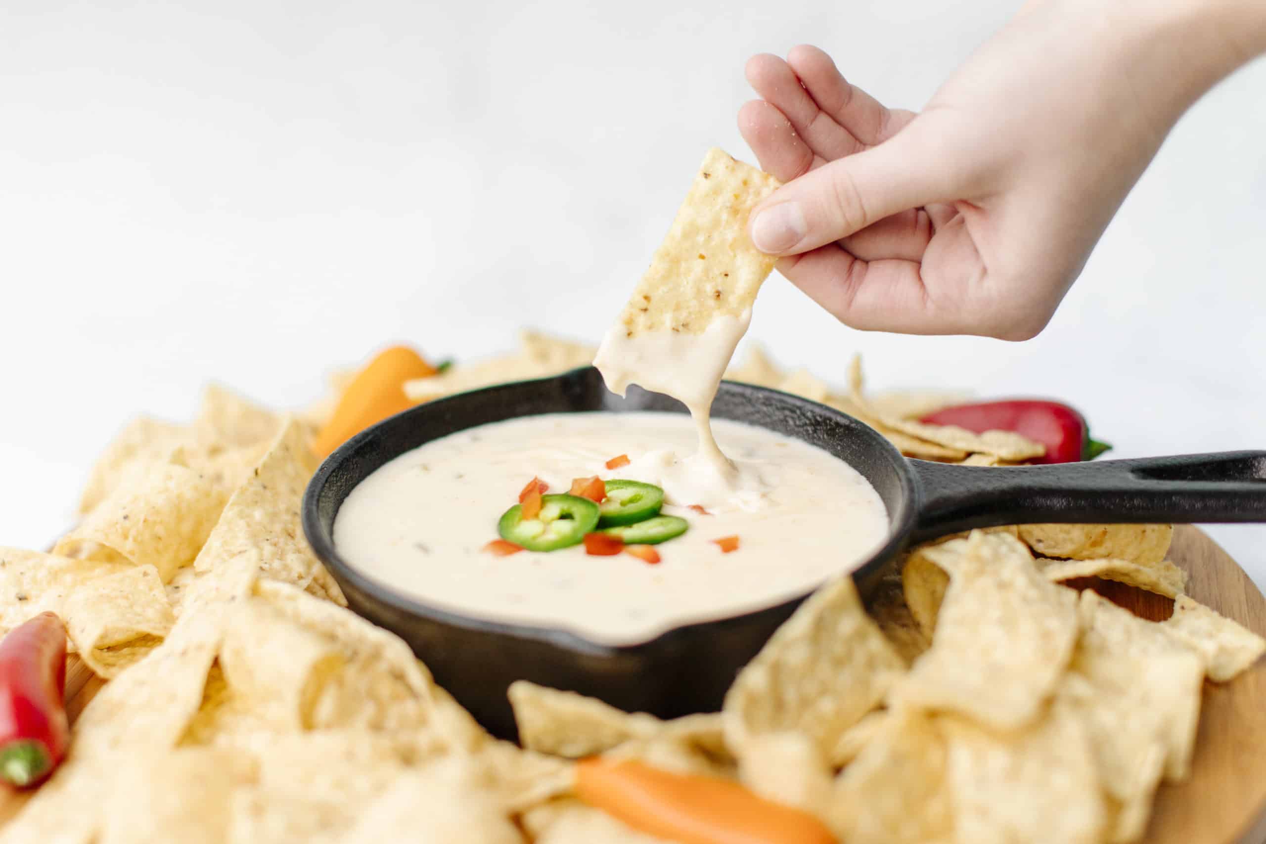 Hand dip the tortilla chips into the white queso dip recipe.