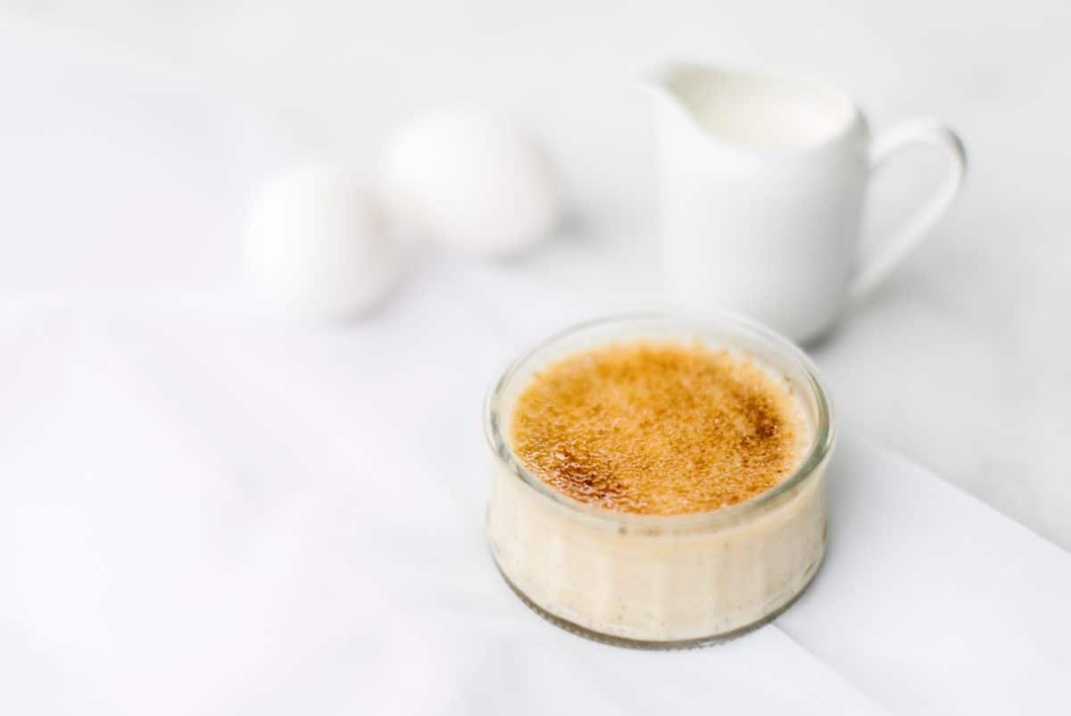 Creme Brulee - Pumpkin Spice in a clear glass jar with a small pitcher of milk and 2 eggs in the background.
