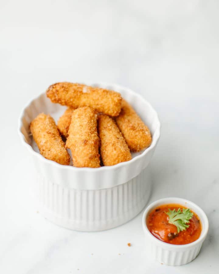 Fried Cheese Sticks Recipe in a serving dish along with a small dish of marinara sauce.