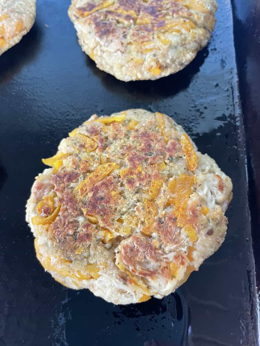 Several Fully Cooked Crab Cakes on a Flat Top Griddle
