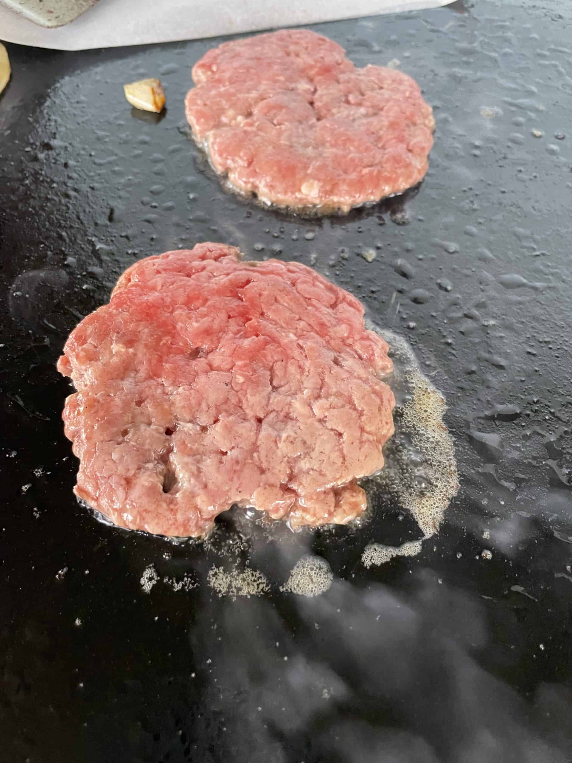 Smash Burgers Cooking on a Griddle.
