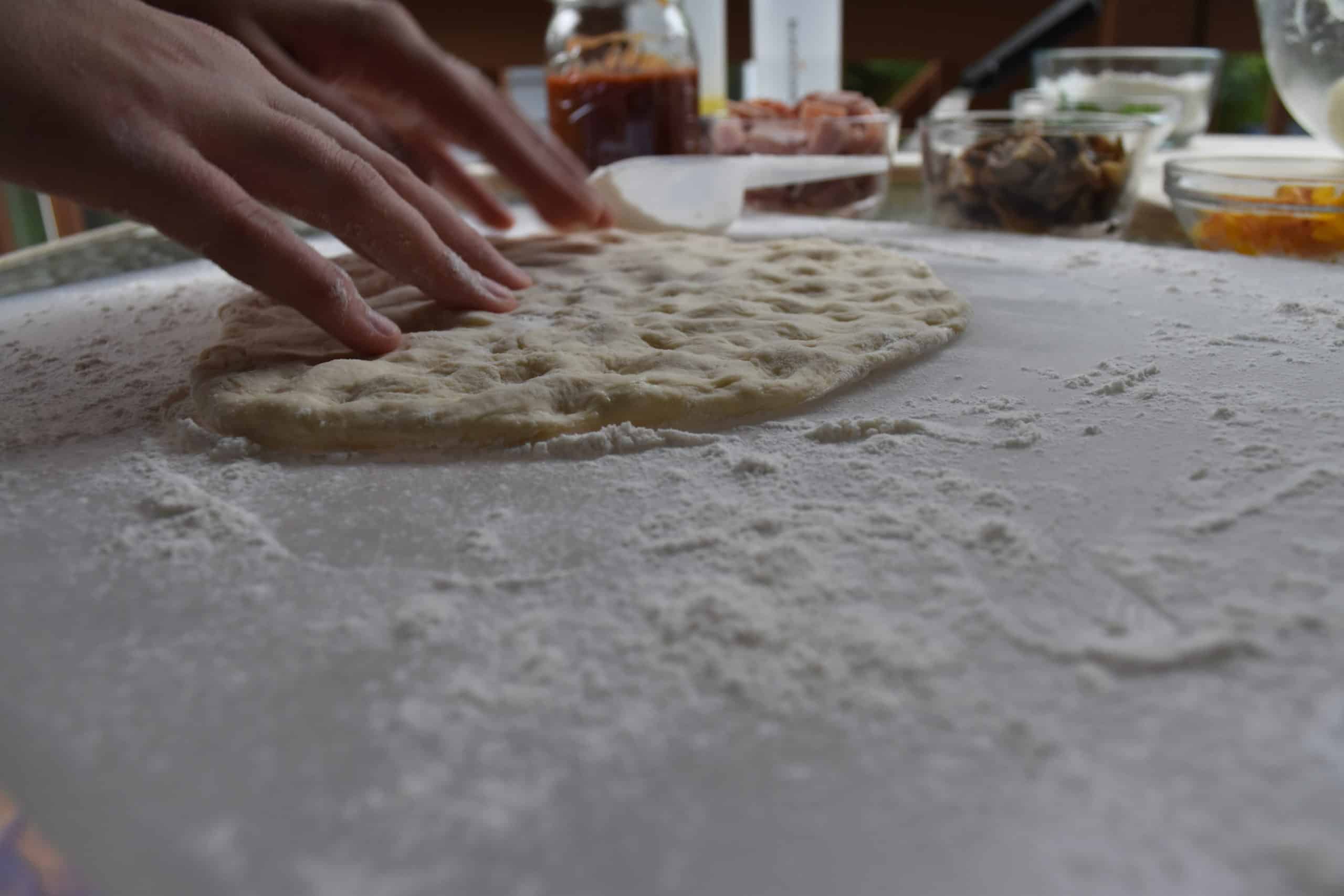 Use fingertip to press pizza dough thin.