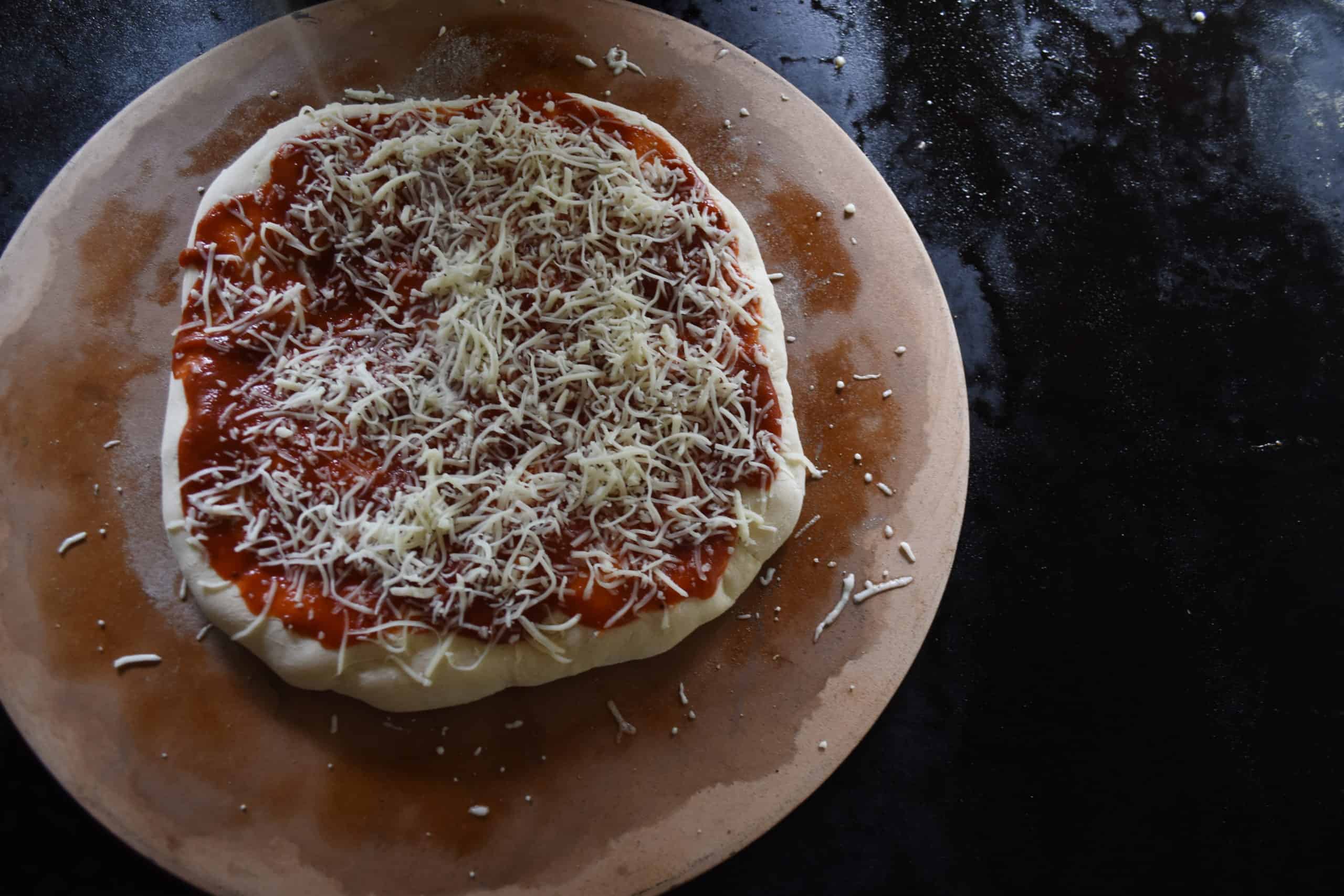 Sprinkle a thin layer of shredded cheese on top of the pizza sauce.