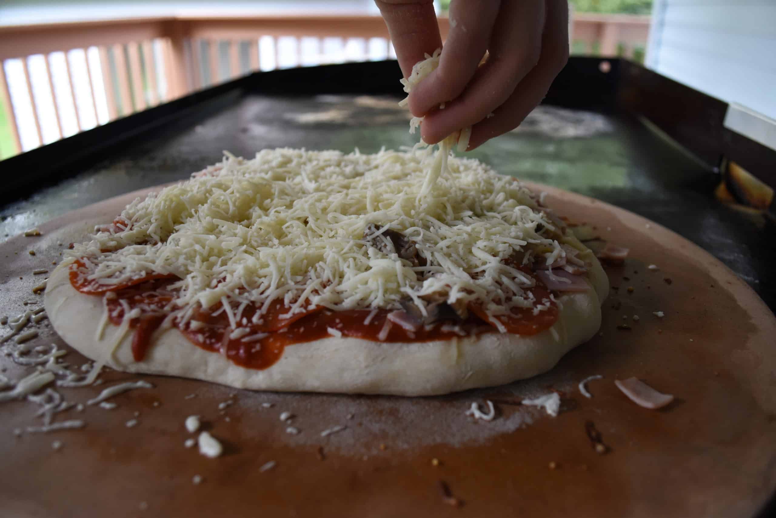 Generously apply shredded cheese to the top of your pizza.