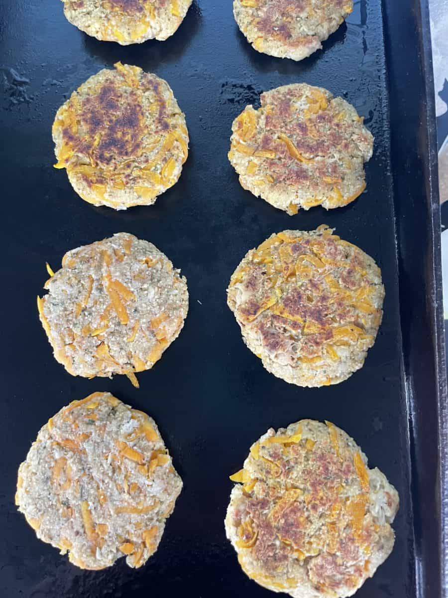 Several Butternut Squash Crab Cakes cooking on a Blackstone Griddle.