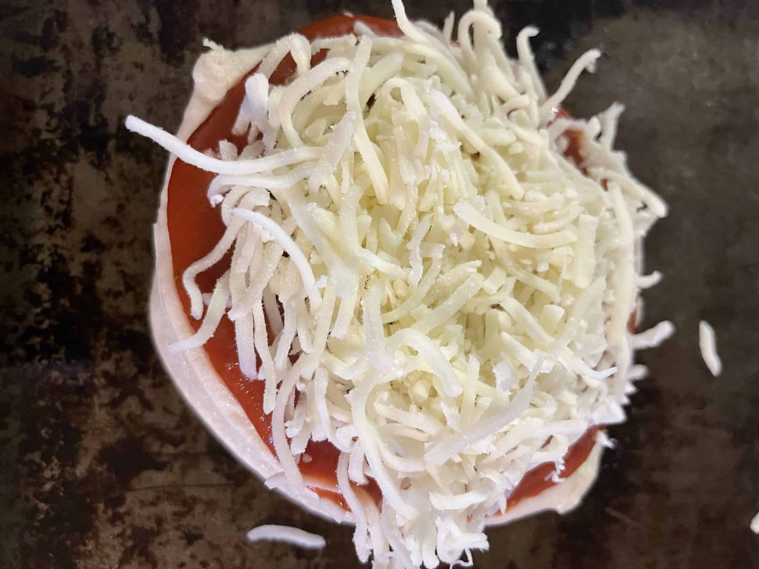 Crust topped with pizza sauce and shredded cheese.