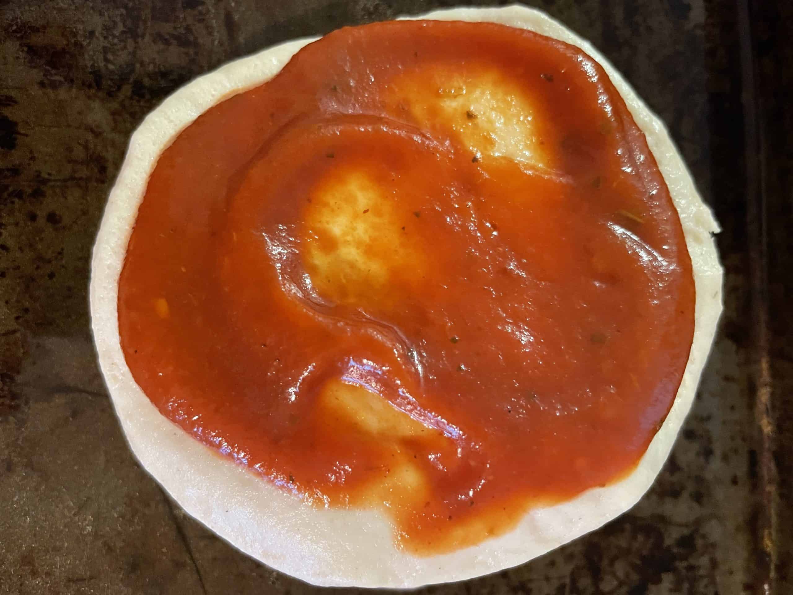 Mini pizza crust topped with pizza sauce.
