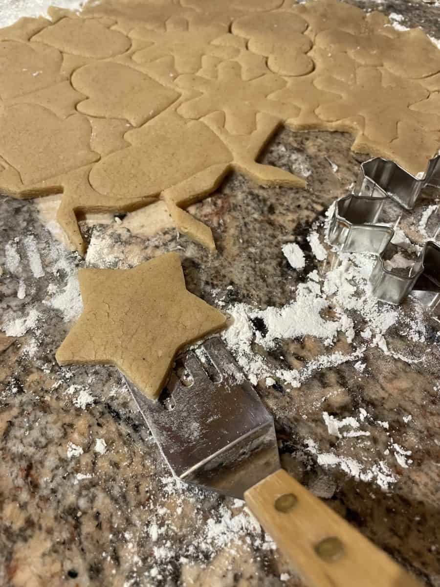 Cutting out spiced sugar cookies on a floured surface.