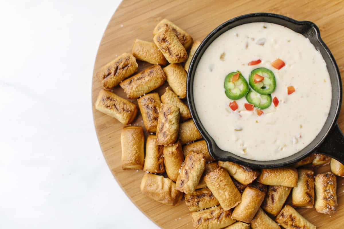 White Queso Recipe in a small cast iron pan surrounded by soft pretzel bites.