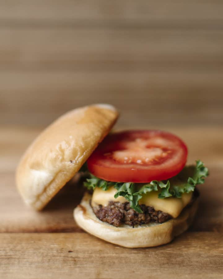Blackstone Smash Burger topped with melted American cheese, lettuce and a slice of tomato.