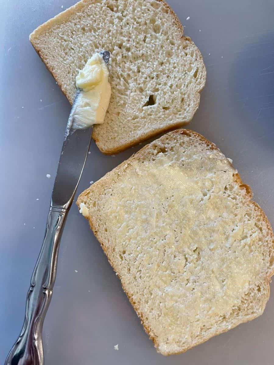 Buttering two slices of white bread.