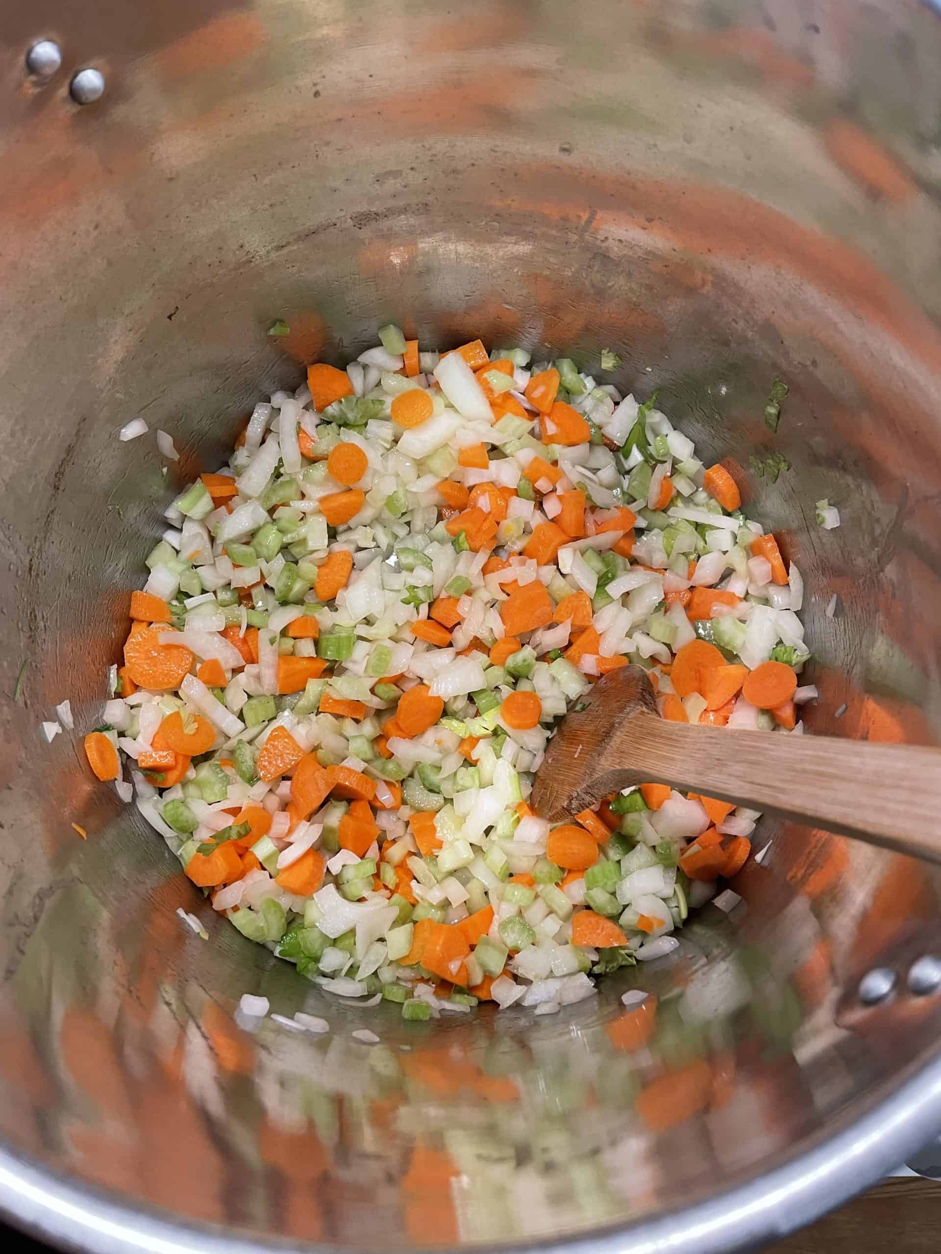 Sautéing the diced carrots, celery, and onions in a large stock pot. 