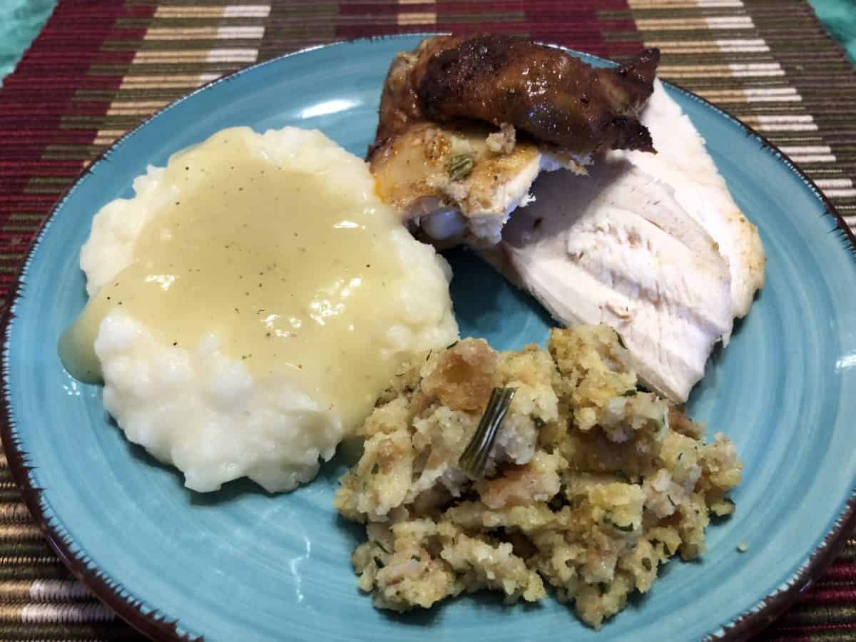 Rotisserie Chicken Pieces on a Plate with Mashed Potatoes and Gravy and a scoop of Stuffing.
