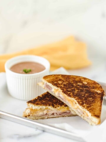 Grilled Ham and Cheese on a plate with a side bowl of tomato soup.
