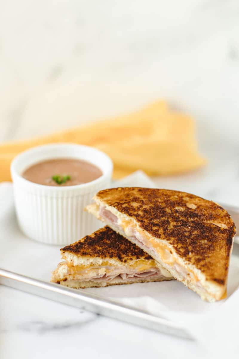 Grilled Ham and Cheese on a plate with a side bowl of tomato soup.