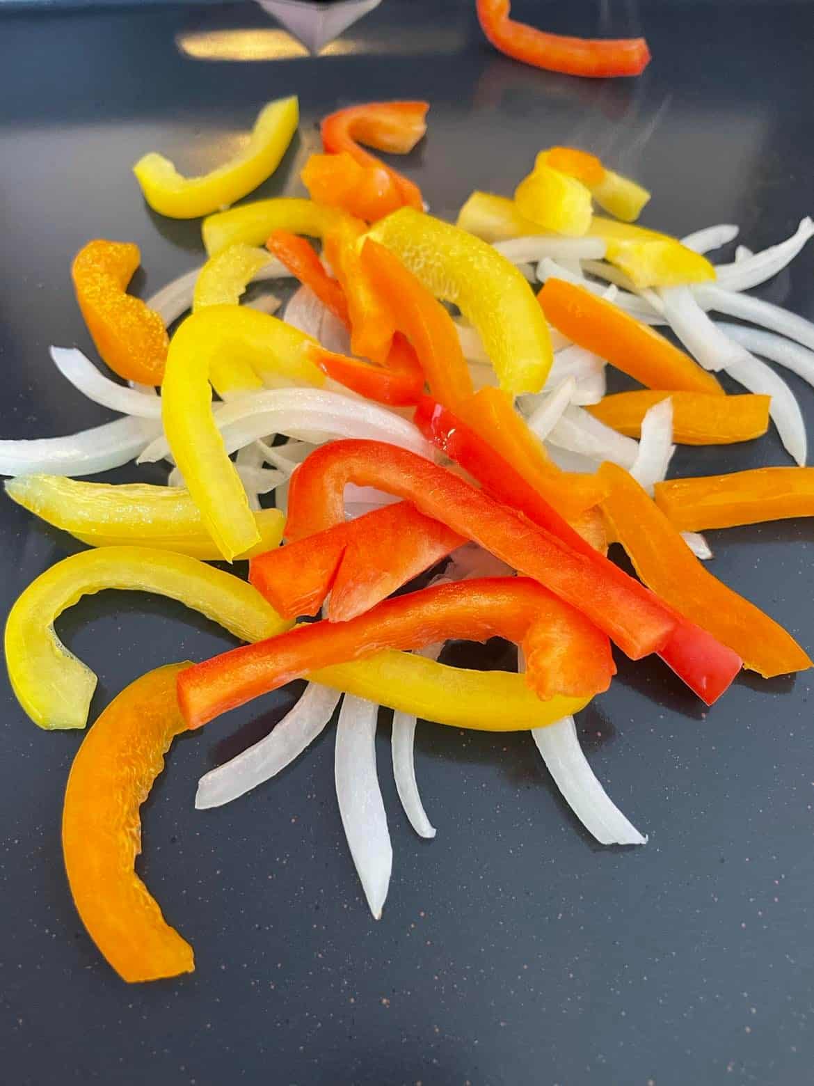 Sliced Onion and Peppers Cooking on a Blackstone Griddle.