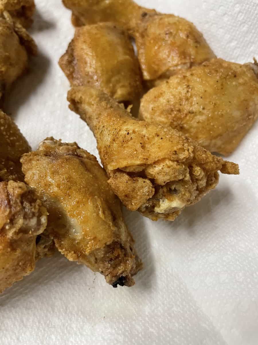 Deep Fried Chicken Wings on a paper towel lined plate.