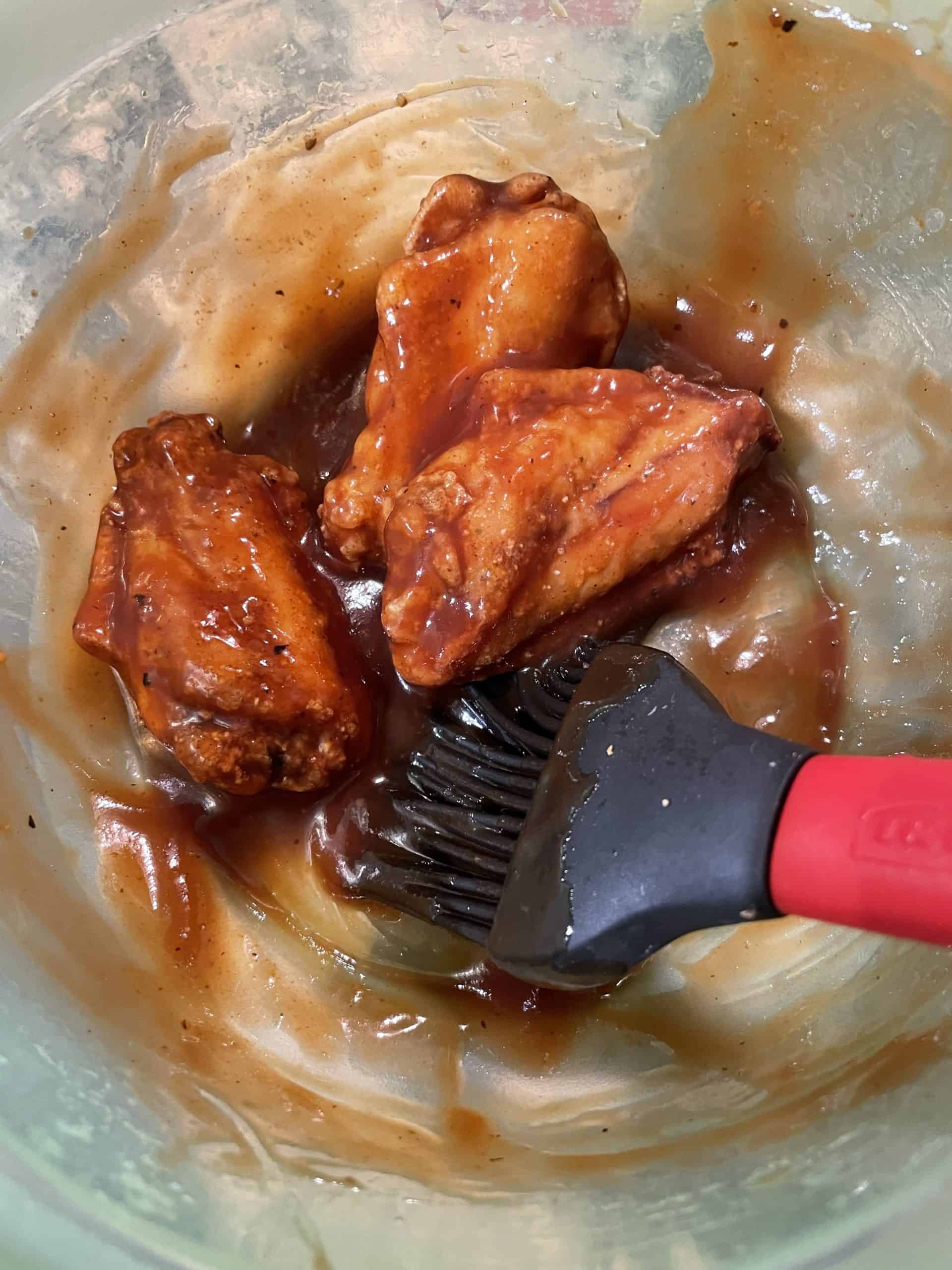 Coating Deep Fried Wings with Sweet Baby Ray's BBQ Sauce  in a bowl with a basting brush.