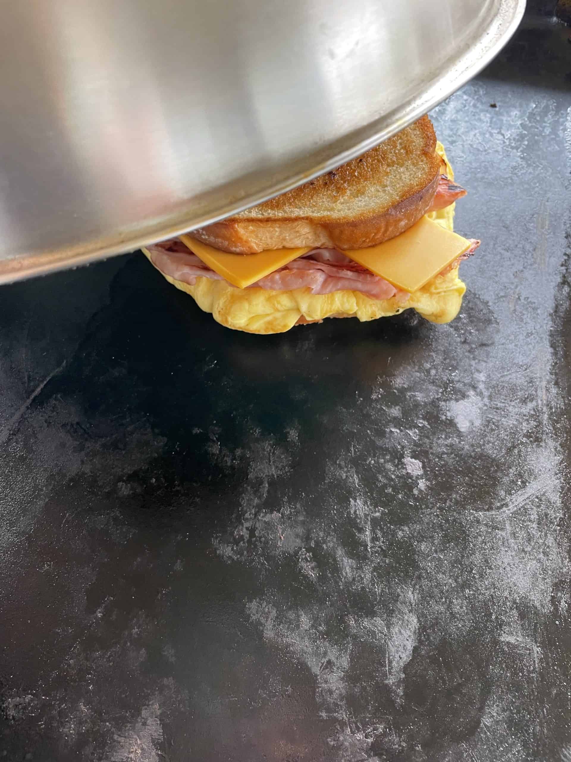 A Dome Lid Covering a Korean Egg Sandwich on a Blackstone Griddle.