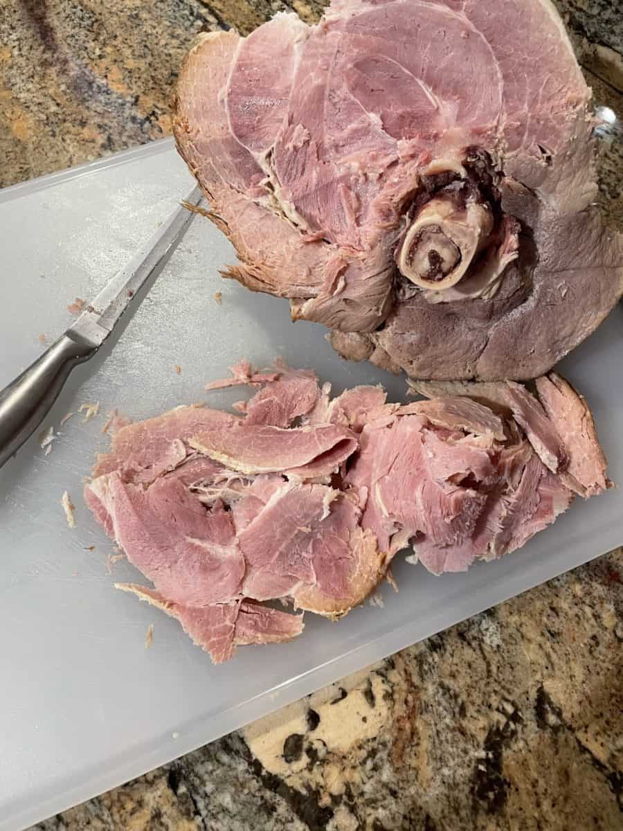 Slicing pieces of a whole boiled ham.