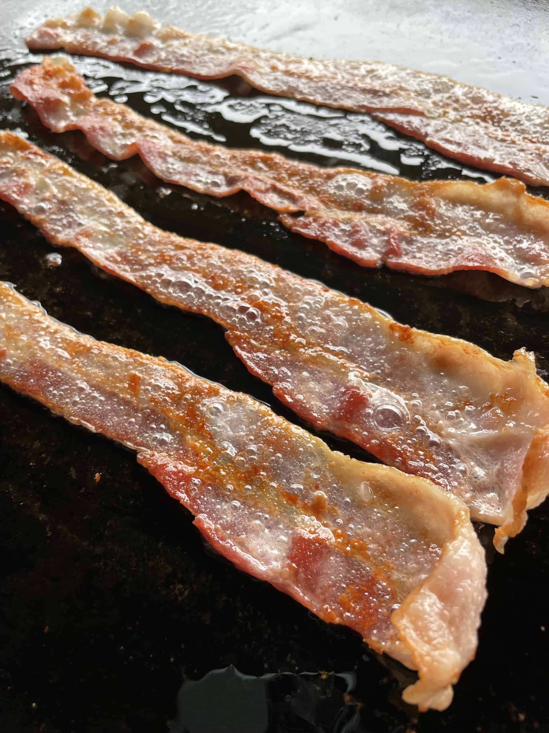 Cooking bacon slices on a Blackstone Griddle.