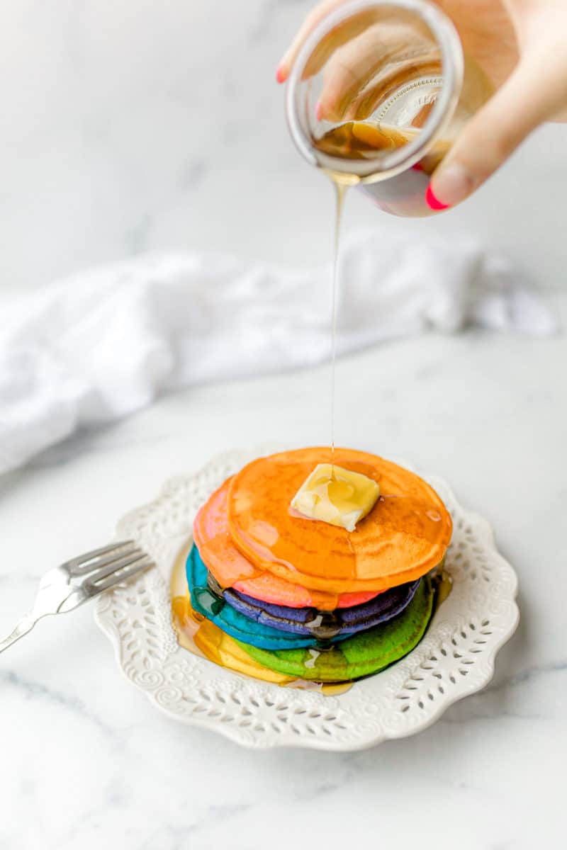 Colorful Pancakes on a Plate topped with a pat of butter and a drizzle of syrup.