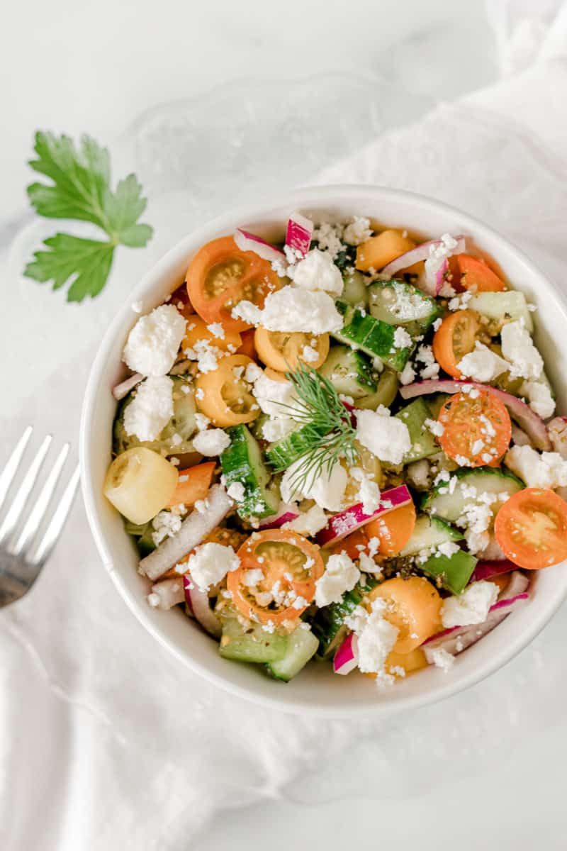 Cucumber Tomato Onion Salad with Feta in a white bowl.