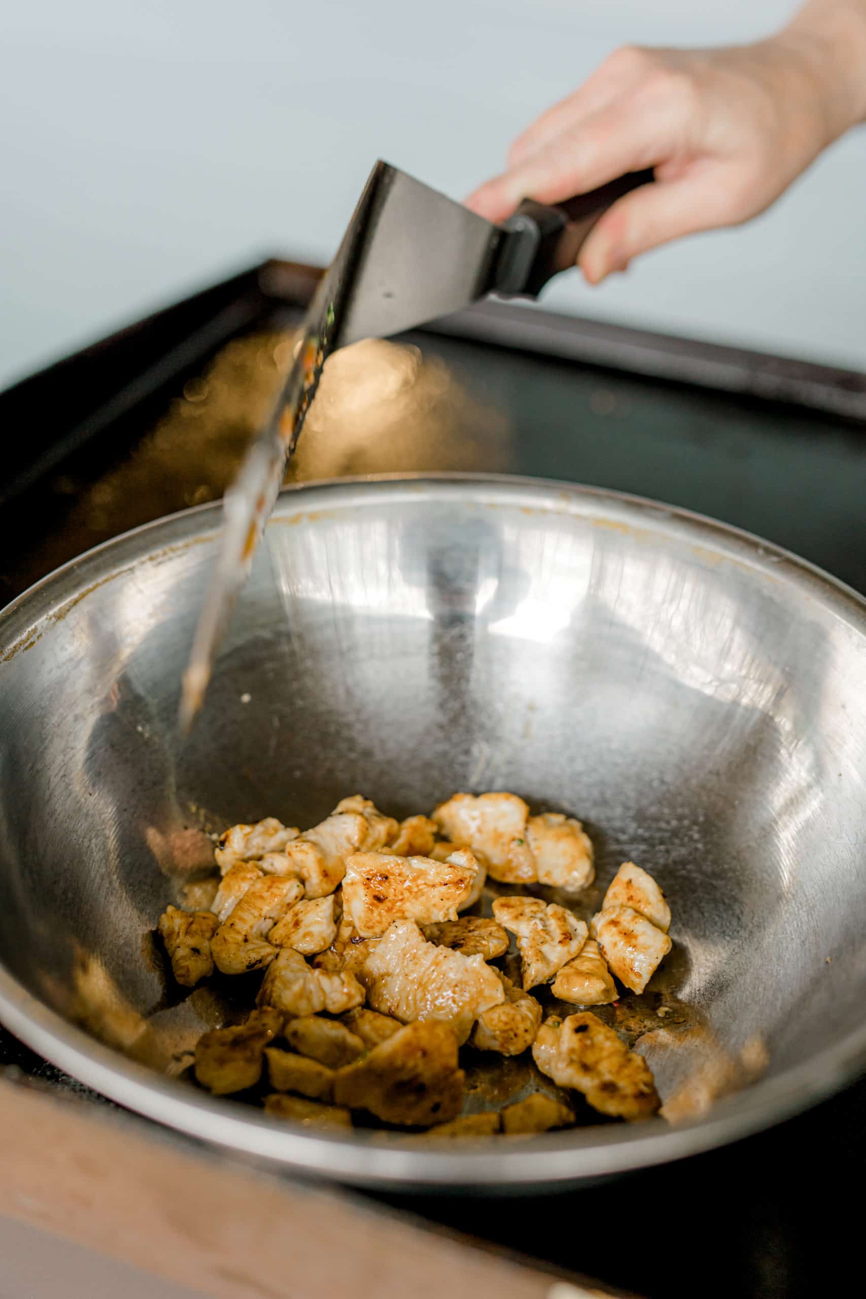 Adding Cooked Chicken to a Stainless Steel Metal Bowl while on the Blackstone Griddle.