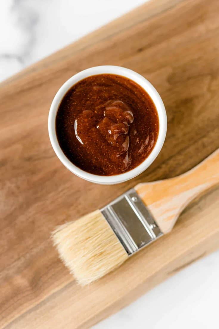 Homemade BBQ Sauce Recipe in a bowl with a pastry brush on a wooden board.