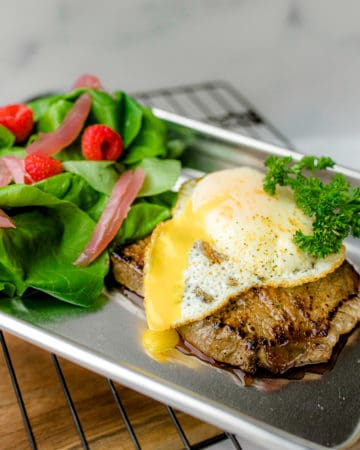 Blackstone Steak and Eggs on a small metal pan with a side salad all on a wire rack.
