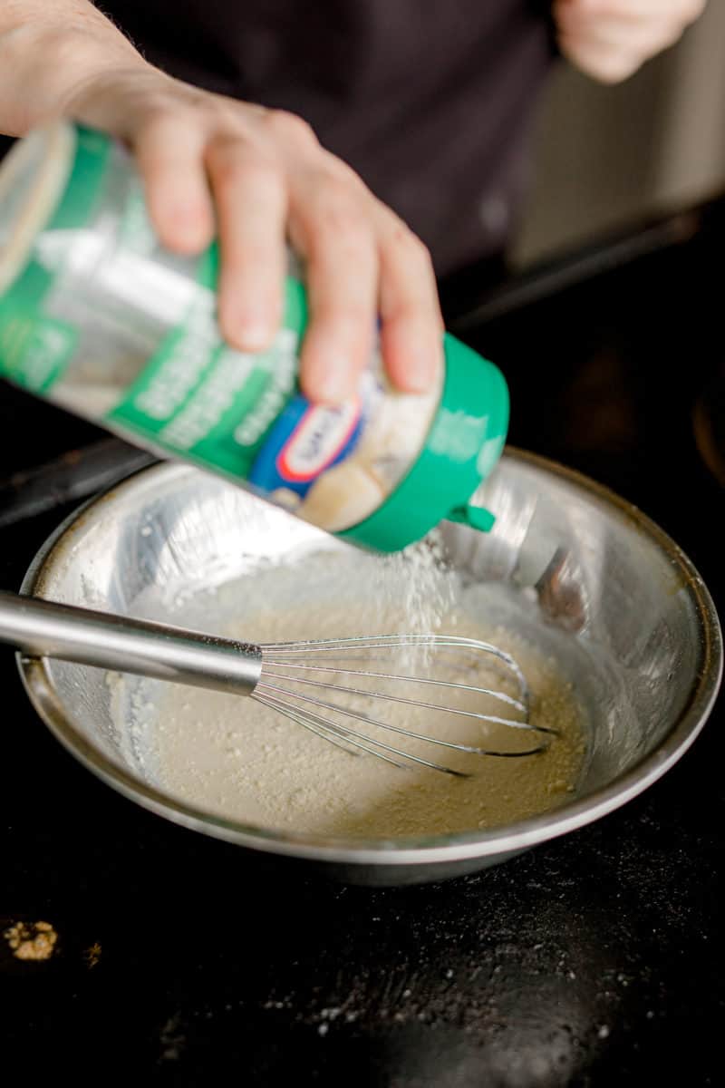 Adding Kraft Bottled Parmesan Cheese to the Milk and Roux Mixture. 