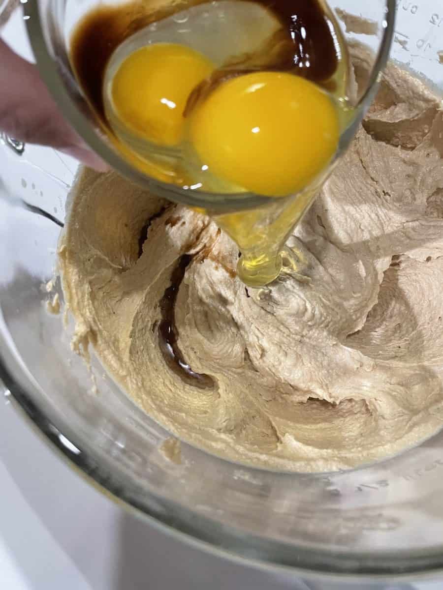 Adding eggs to the Creamed Mixture in a mixing bowl.